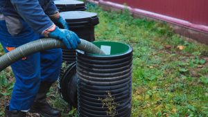 worker maintaining septic tank system, pumping sewage outdoors