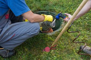 Worker  cleaning and unblocking septic tank in a client's backyard. 