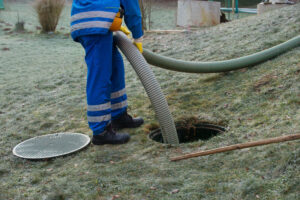 Man working on septic tank on property with frosted grass