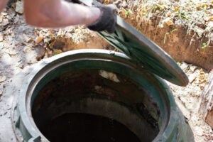 Septic take professional lifting hatch of an old septic tank to see how worn down it is
