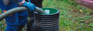 worker maintaining septic tank system, pumping sewage outdoors