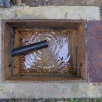 A septic tank has a hose in it and is being cleaned out.